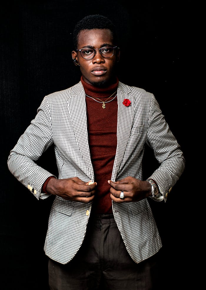 Portrait of a stylish young man wearing glasses and a checked blazer, exuding confidence.