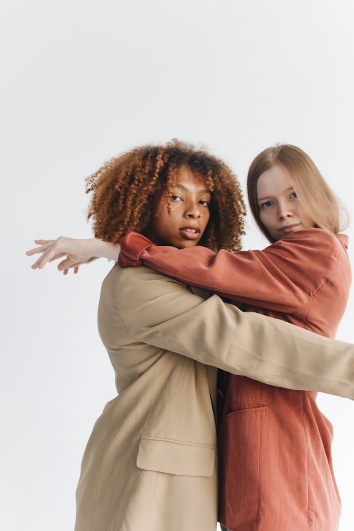Two women in stylish blazers embracing, showcasing friendship and fashion.